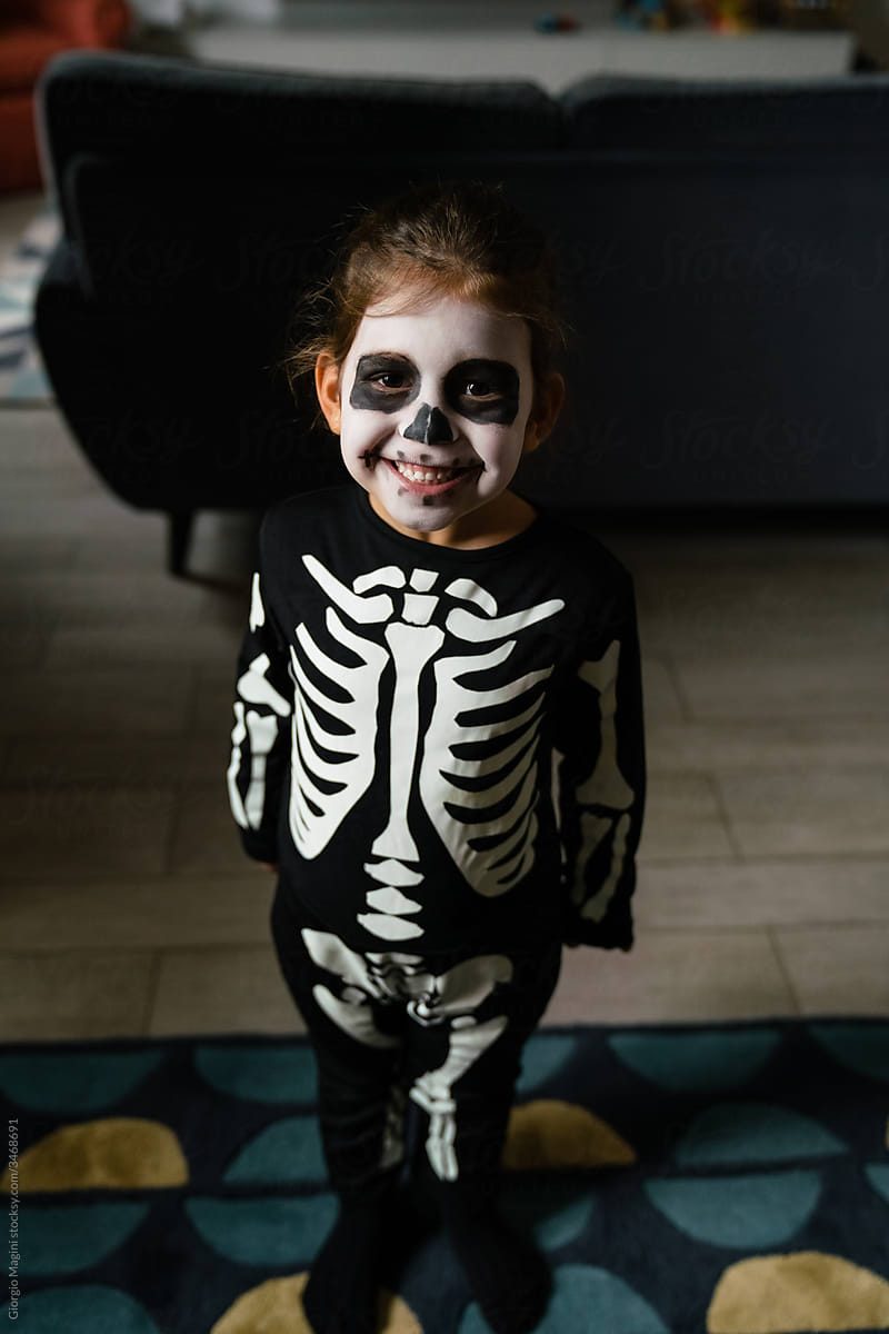 Delighted girl in skeleton costume at home