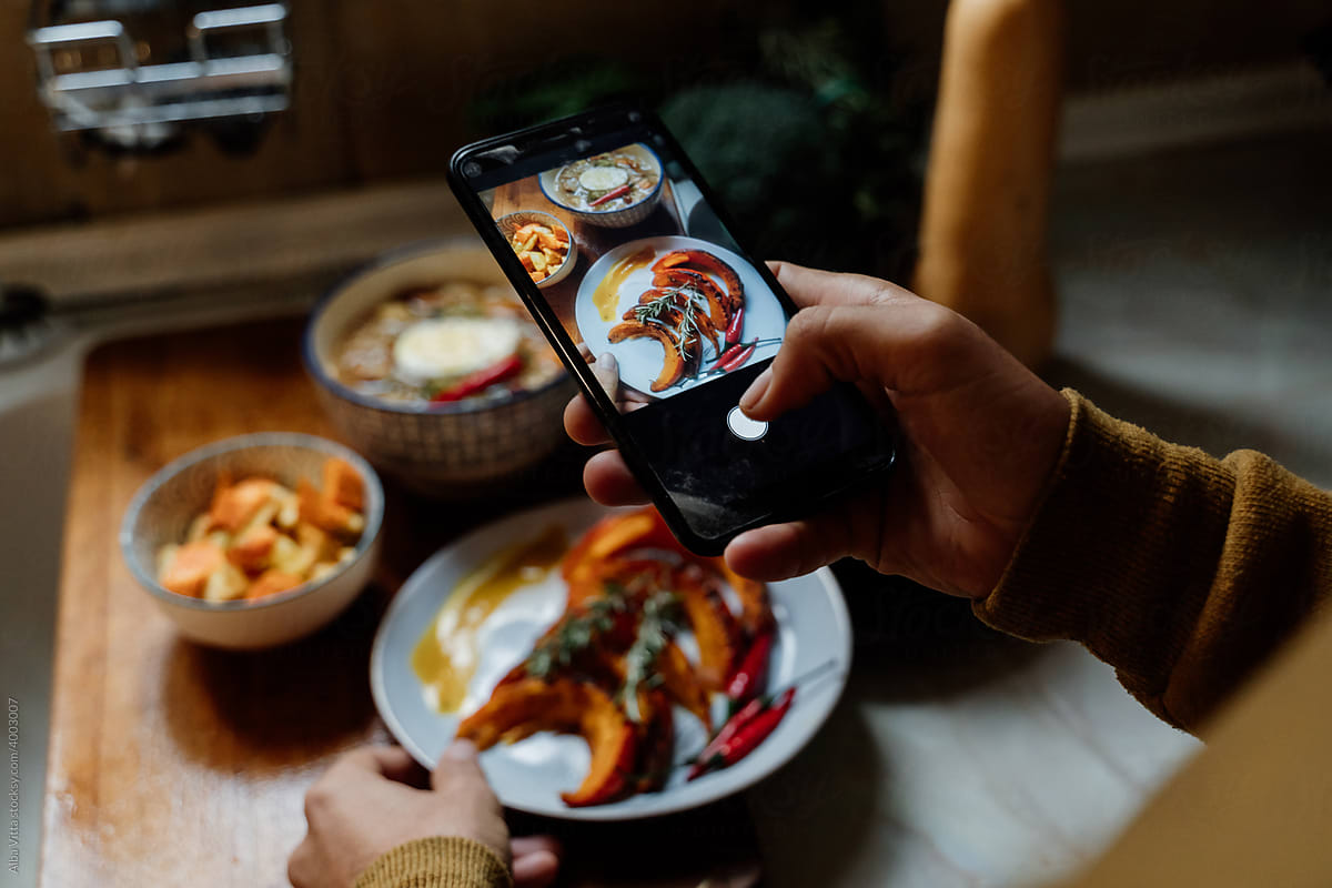 Man taking photo with phone of healthy dishes