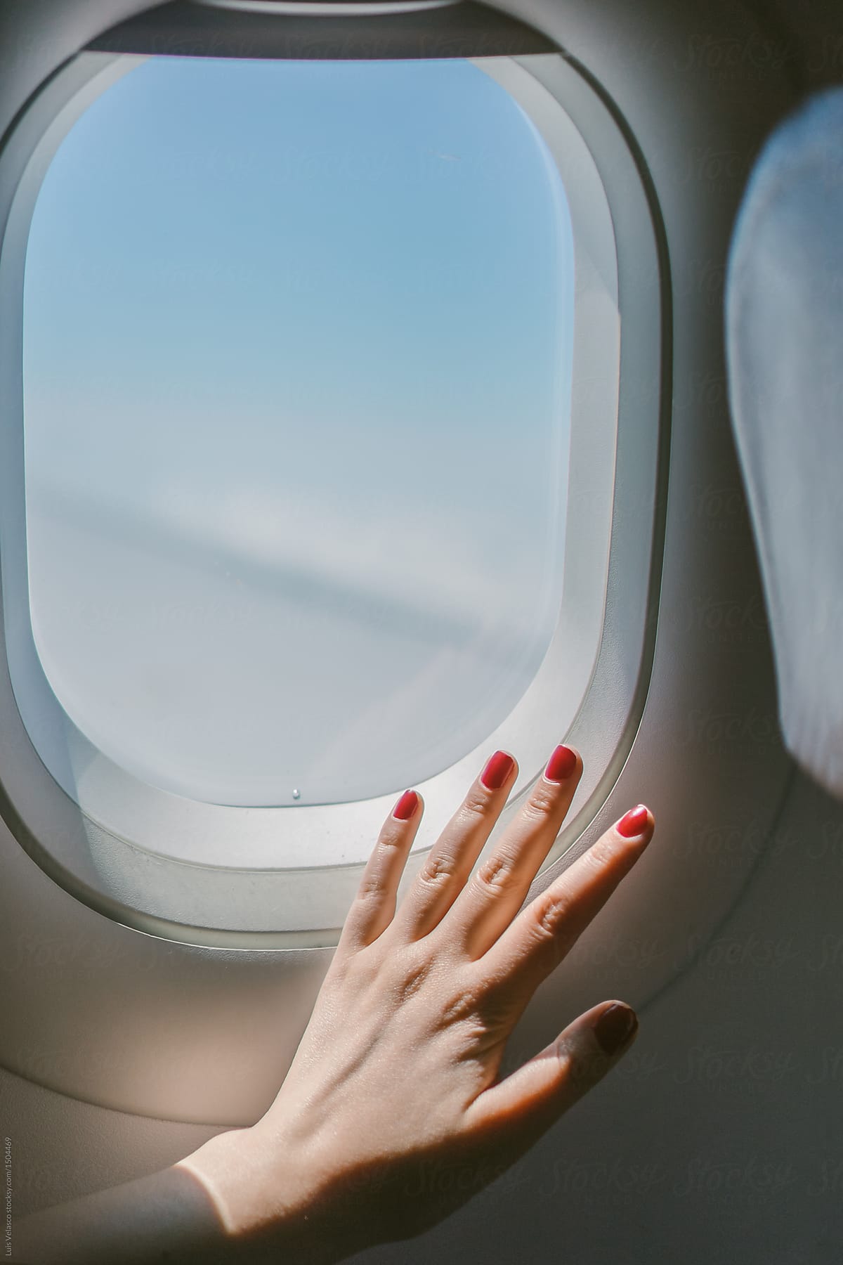 Airplane Window With Female Hand With Red Nail Polish.