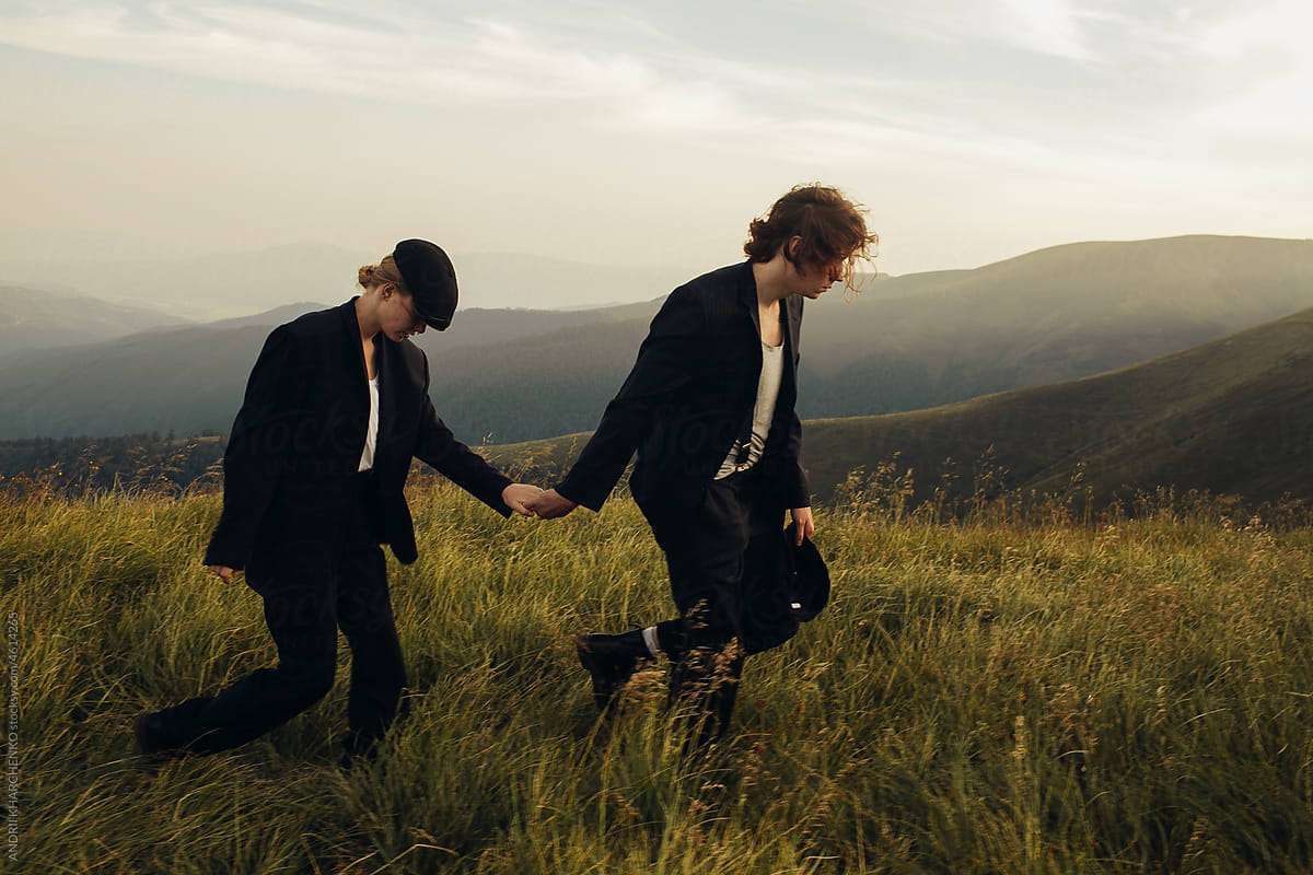 Stylish couple in black suits on a walk among mountain landscapes
