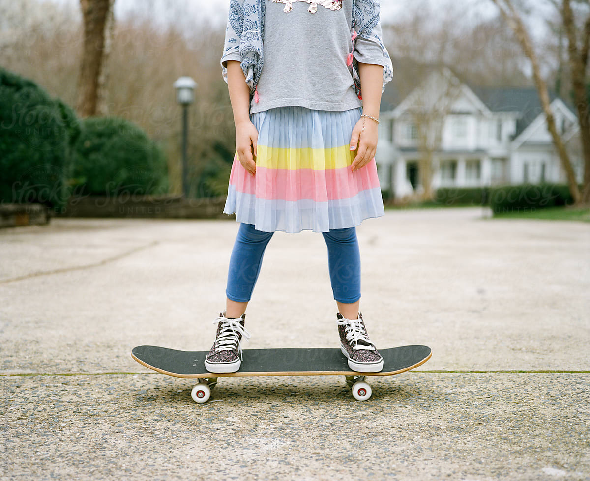 Young girl in a colorful outfit standing on a skateboard