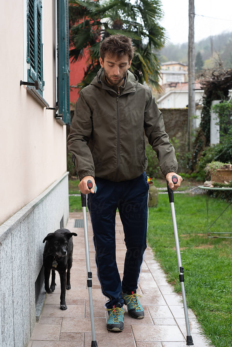 Cautiously walking with crutches with dog