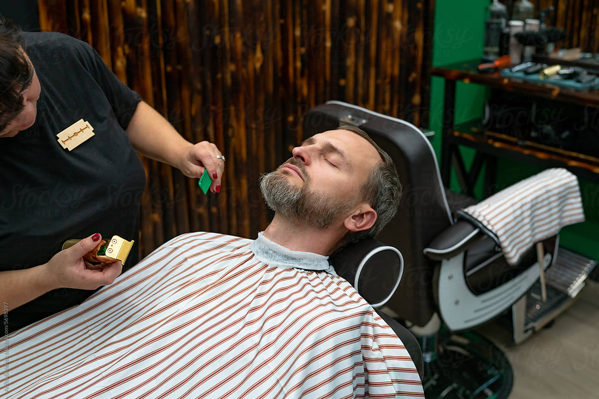 man having his beard cut by electric shaver