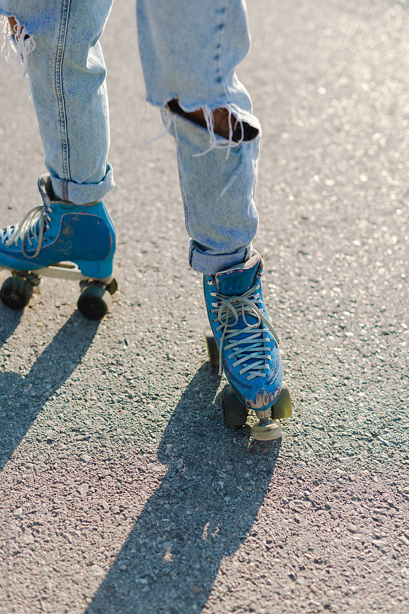 Roller-skater\'s legs with old blue skates in sunlight
