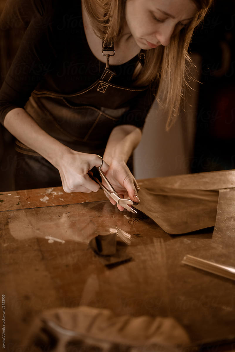 Woman puncturing leather