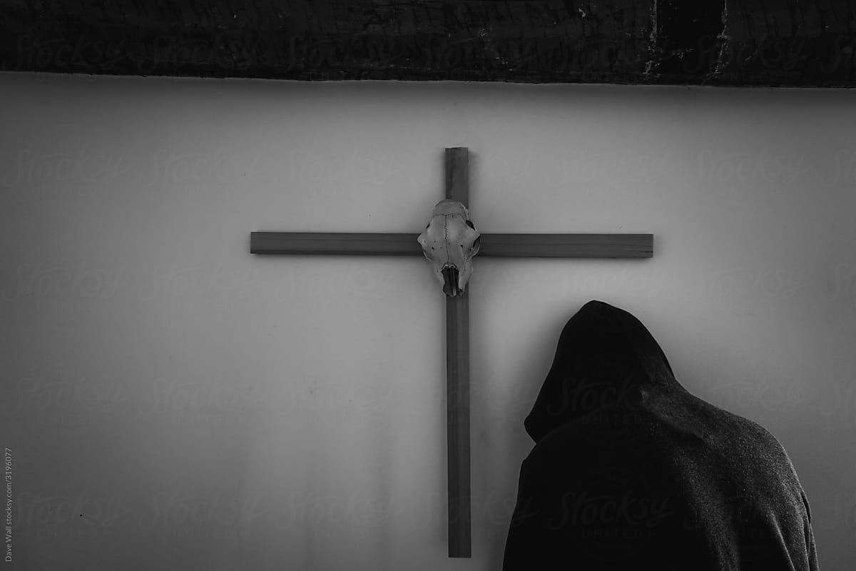 A horror concept of a hooded figure next to a cross.