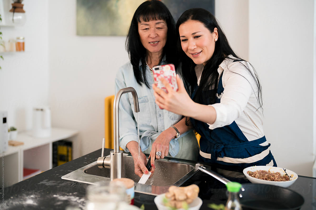 Content Japanese women taking selfie in kitchen at home