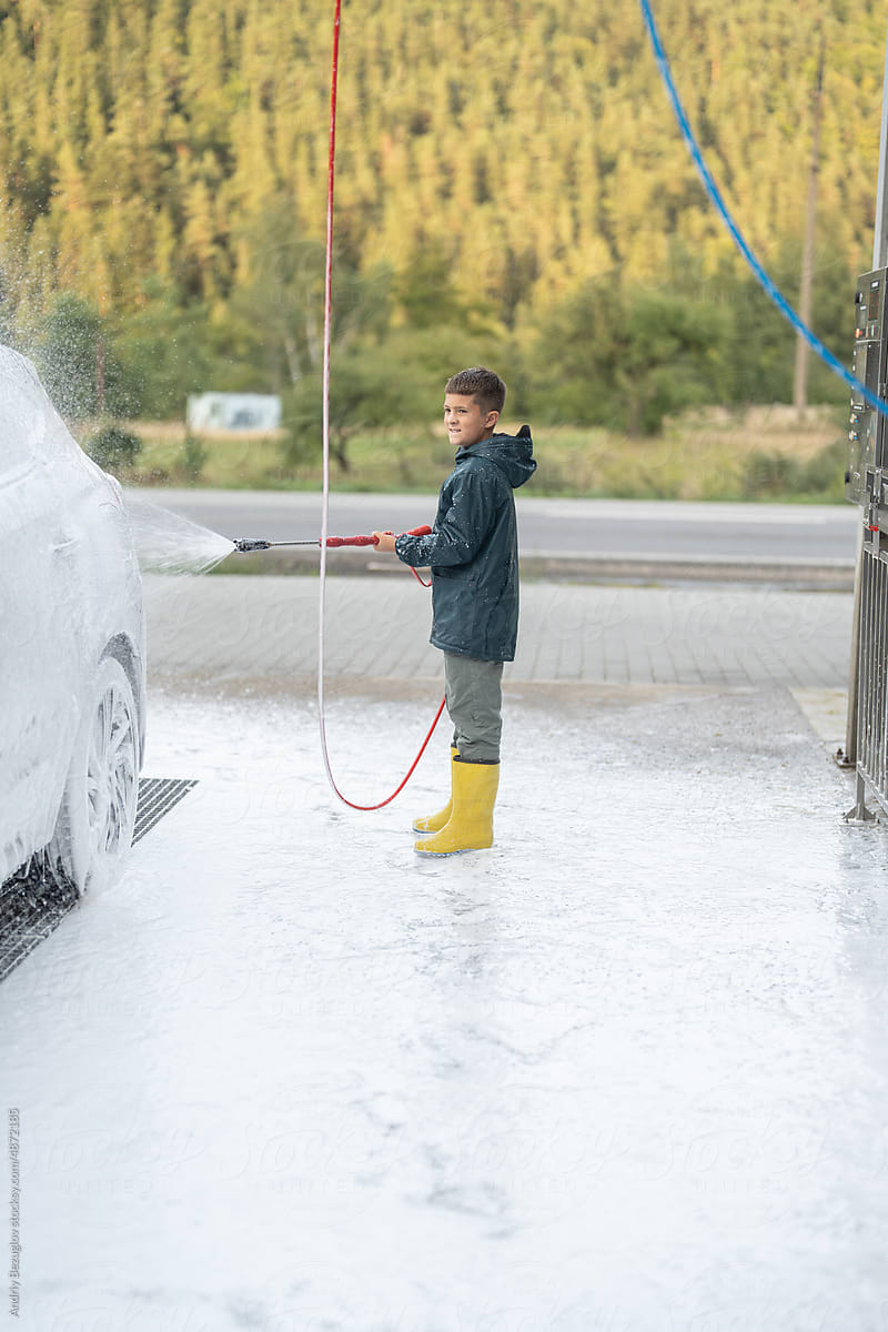 Kid is washing vehicle at manual car wash station
