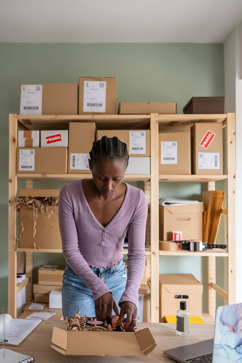 Black employee packing beauty products in container