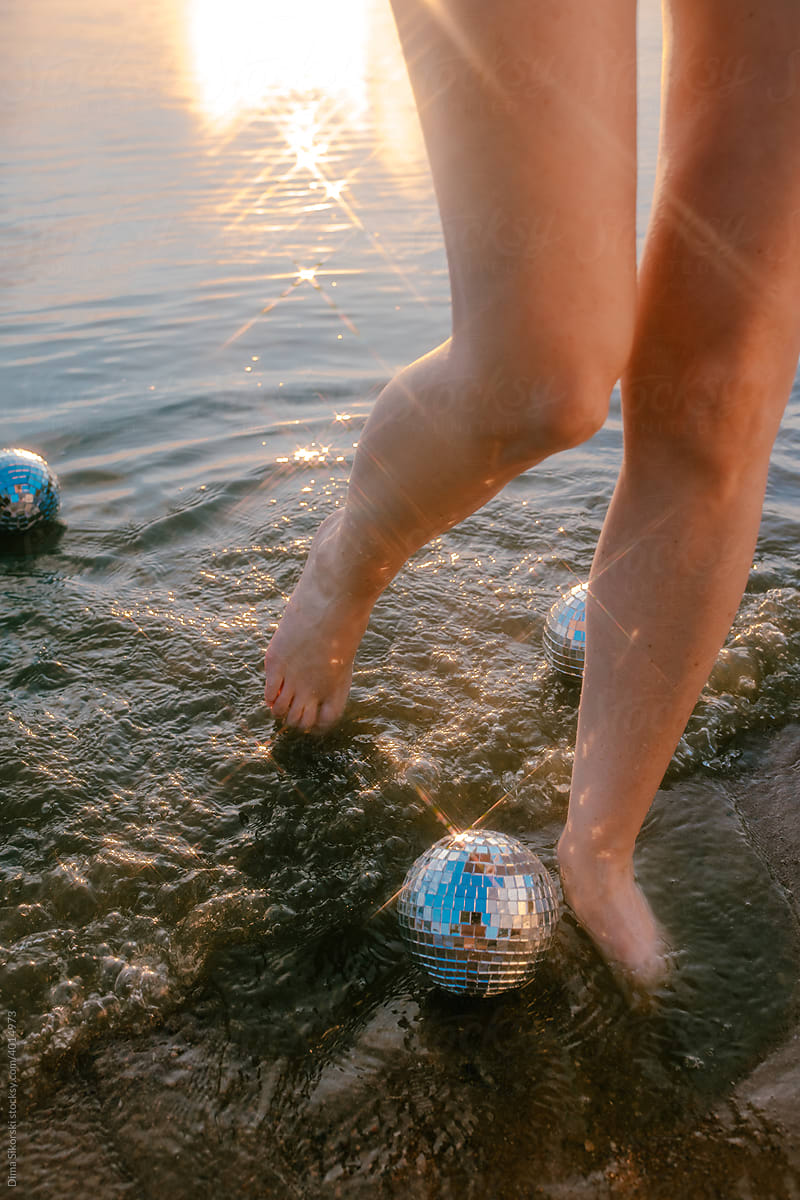 feet in the sea with mirror balls