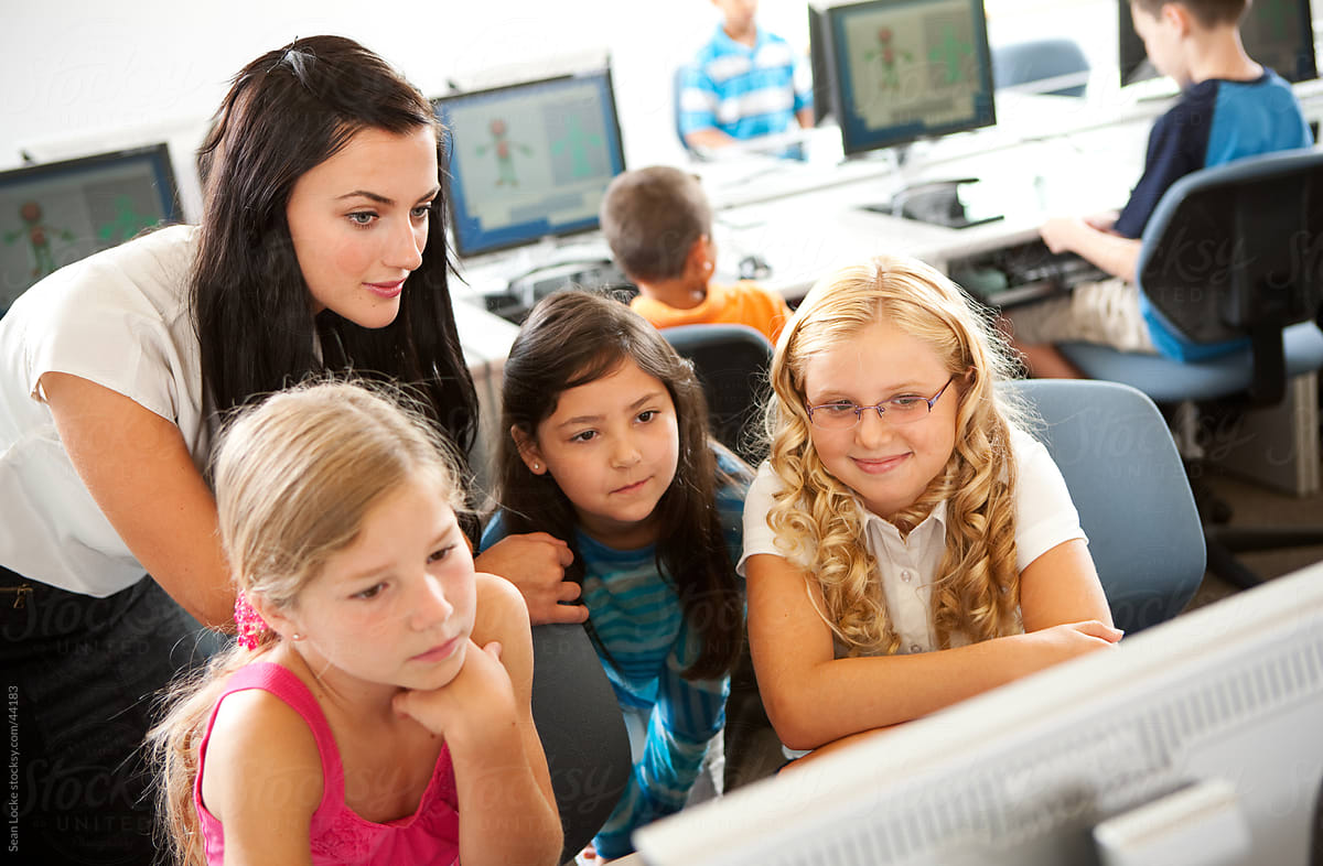 Computer Class: Teacher Assisting Girls with Work
