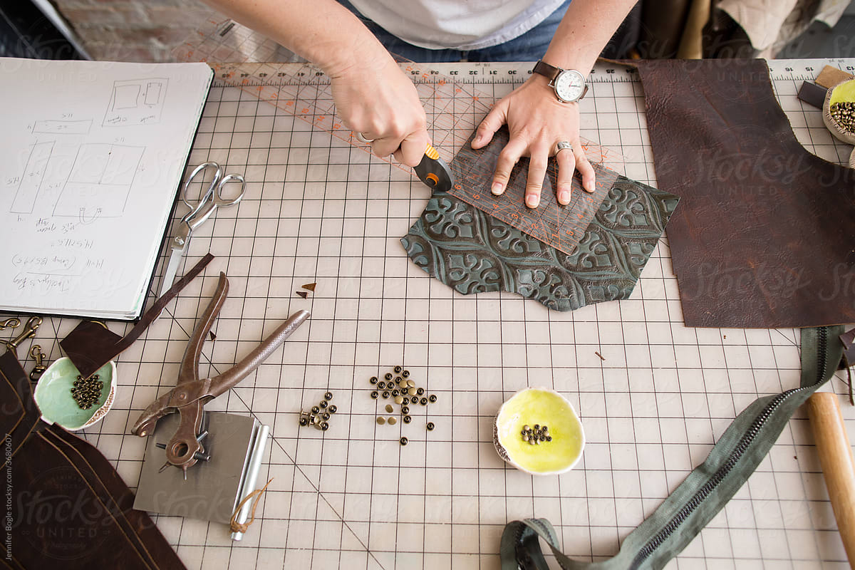 Artisan trims leather with rotary tool at work table