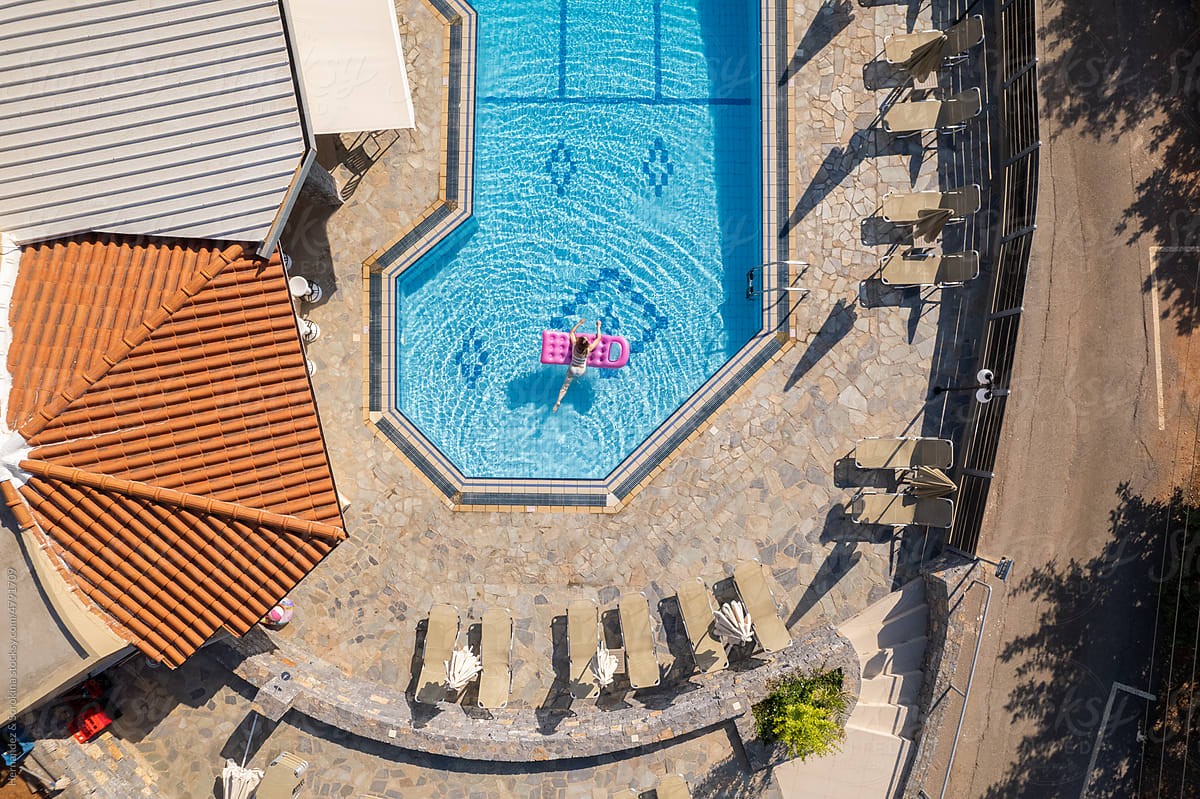 Woman Floating On Air Mattress In Resort Pool