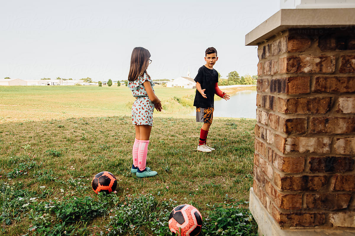 Siblings practice soccer in backyard