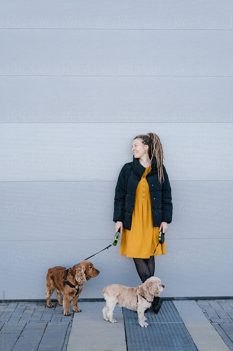 Female owner with dogs leaning on wall