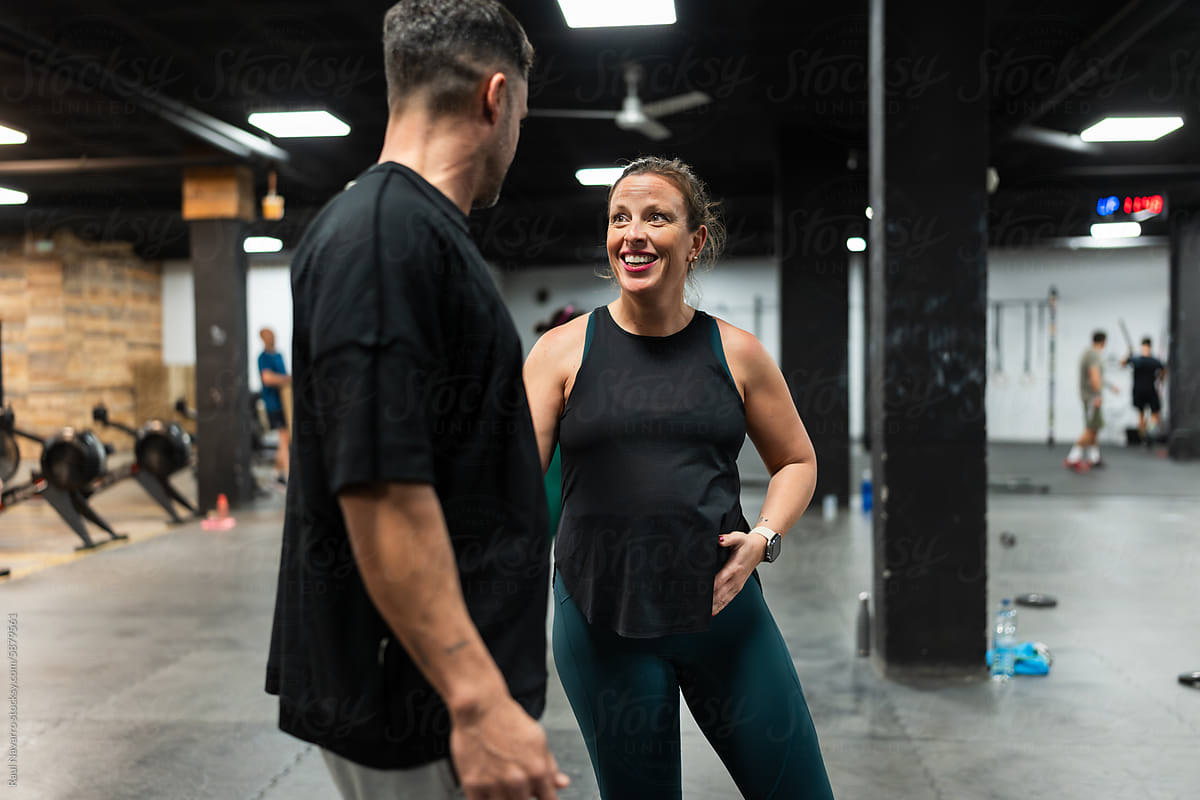 Smiling pregnant woman talking to her trainer in the gym