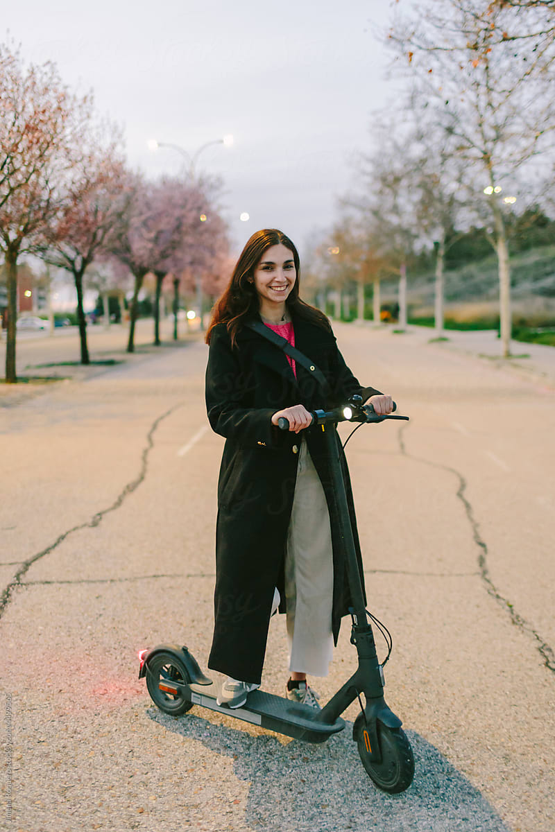 Woman posing at sunset with e-scooter in the street