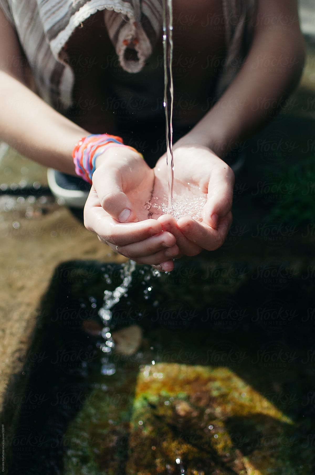 Water Flows from a Fountain into a Girl\'s Hands