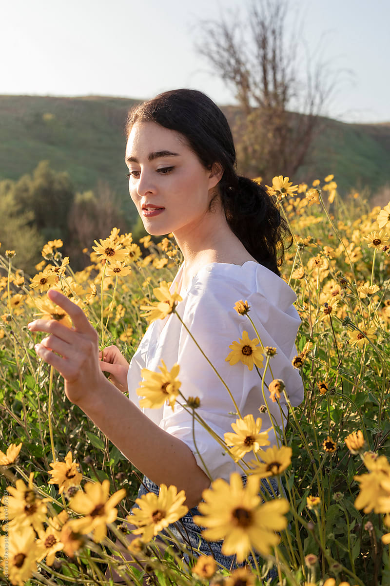Attractive young woman in field of yellow flowers