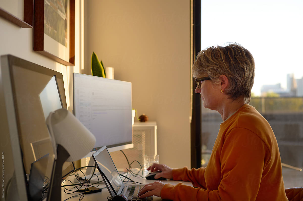 Woman working from home using multi screen set up