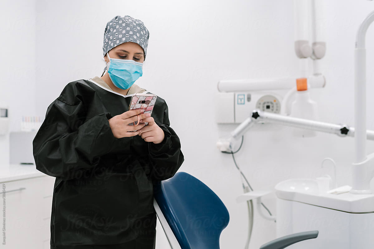 Dentist with mask using smartphone.