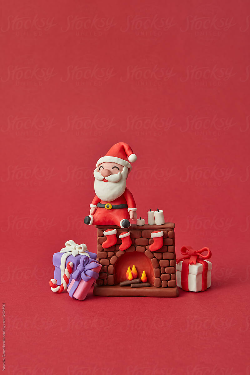 Plasticine Santa Claus sitting on fireplace with gifts.