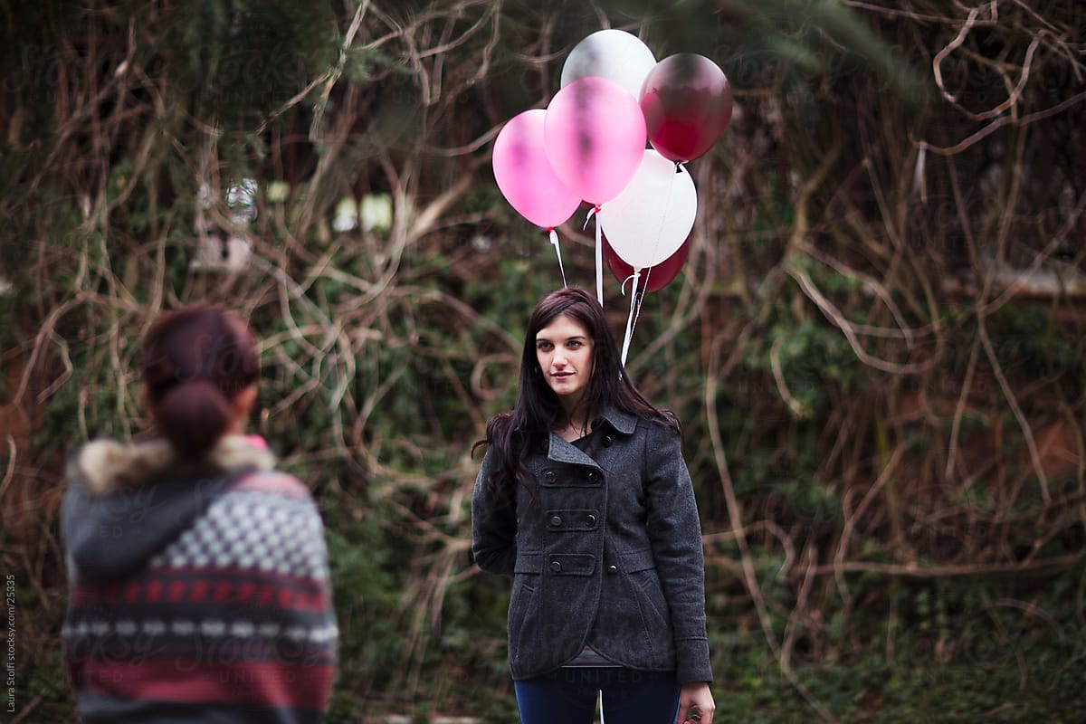 On an external set: photographer taking pictures of a girl standing with bunch of balloons