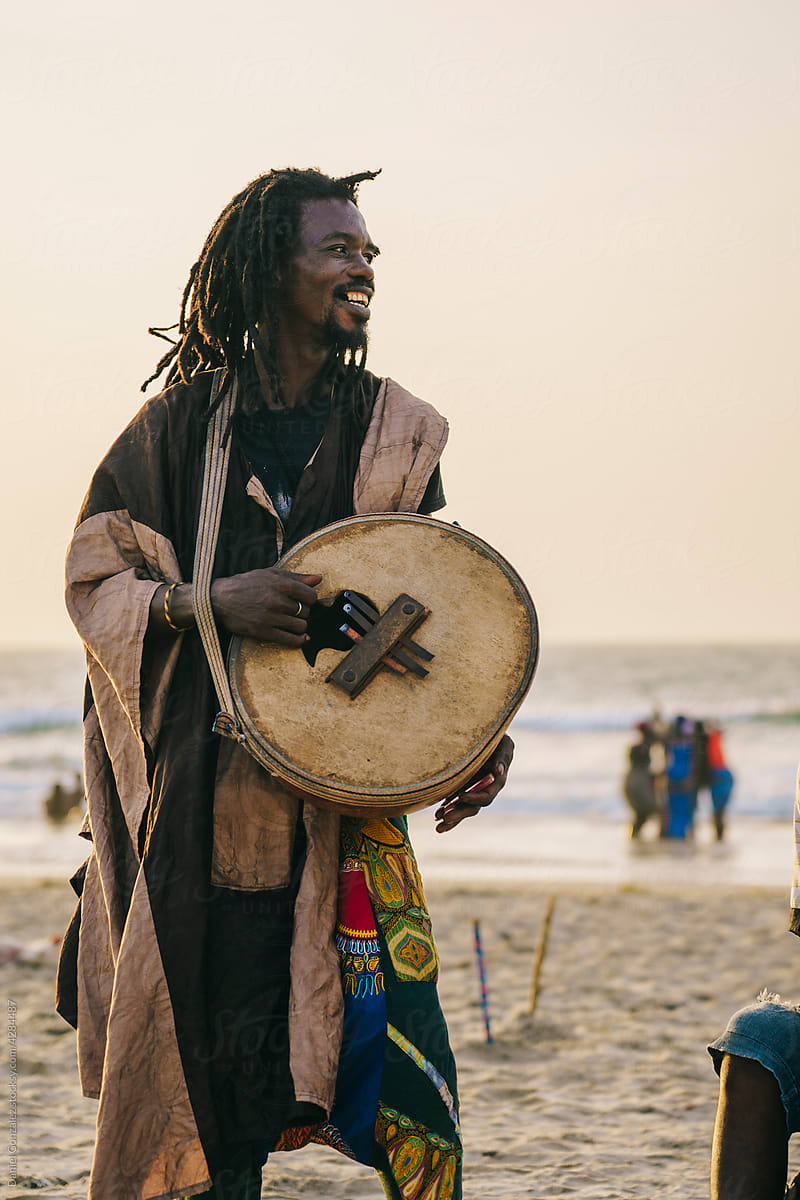 African male playing gongomah near ocean