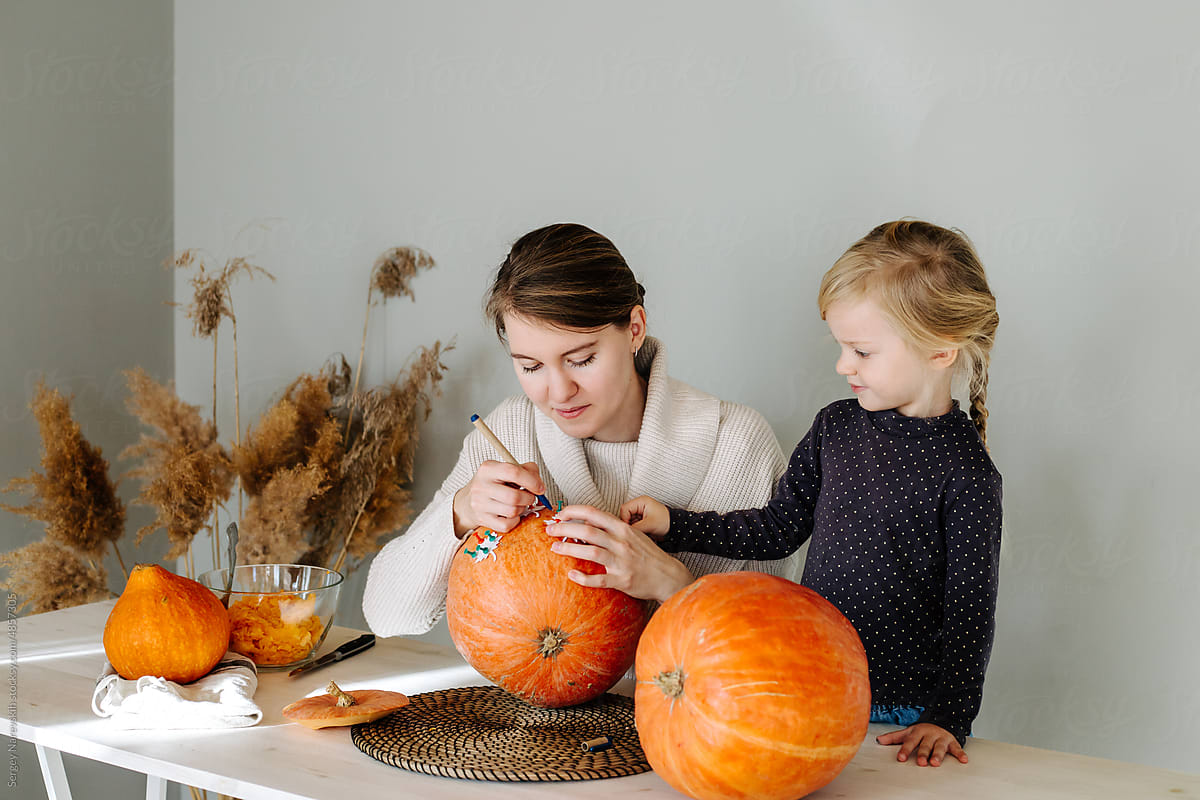 Mother and daughter preparing pumpkin for Halloween holiday