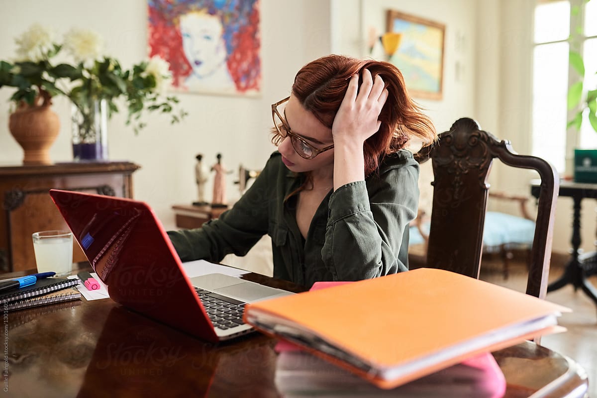 red-haired woman working at vintage desk.