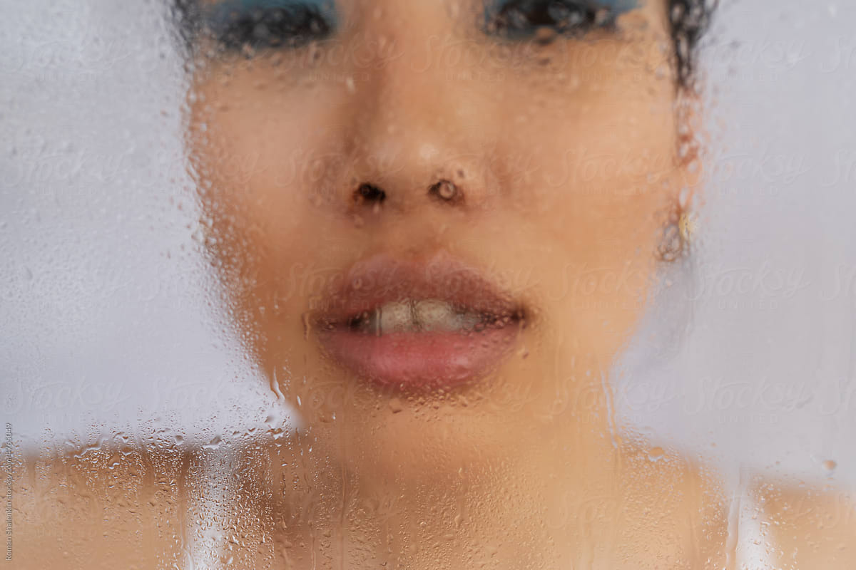 Through wet glass of Asian woman