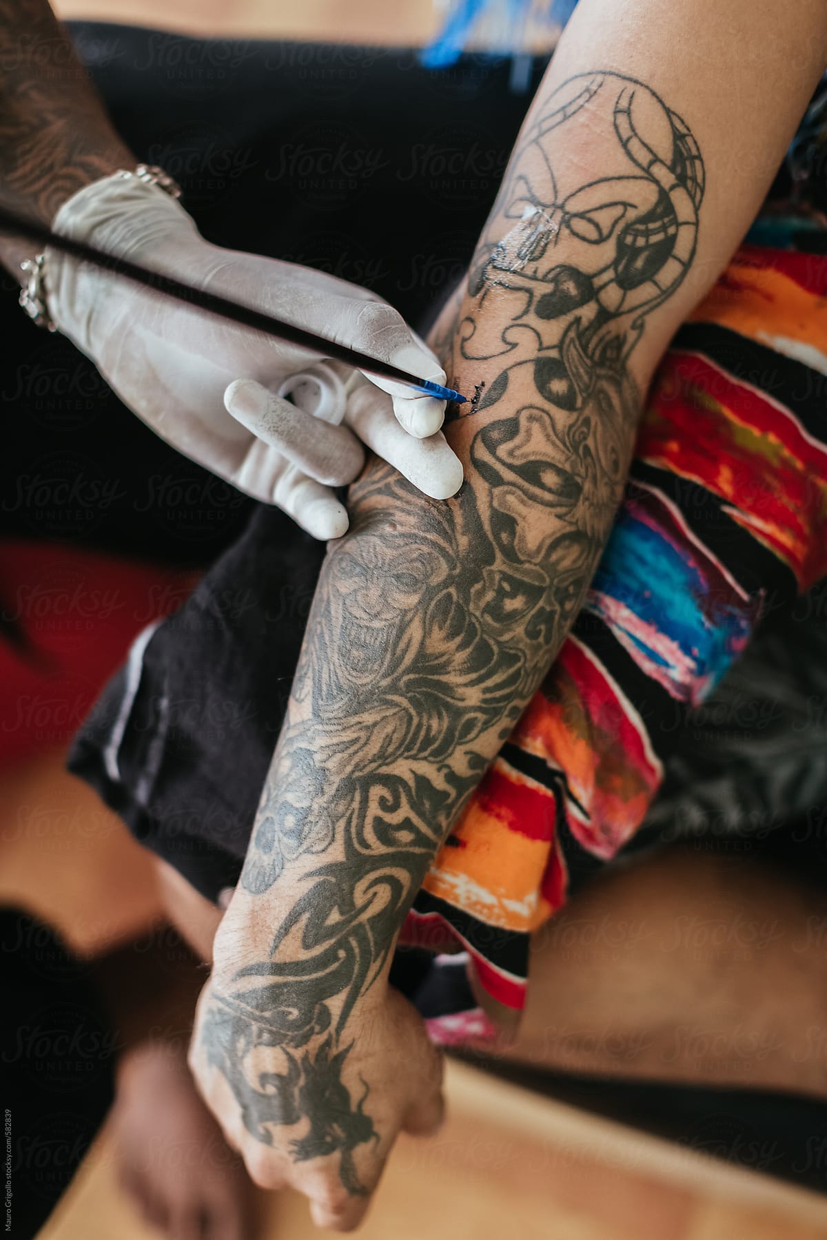 Thai tattoo artist working on a tattoo inside his studio