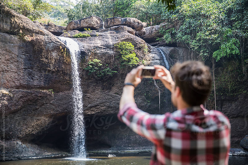 Man taking a photo of a waterfall
