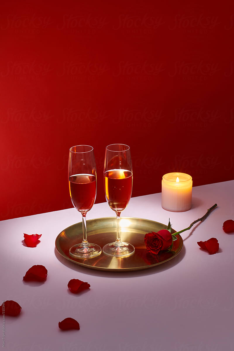 Two glasses of pink rose wine on golden tray background.