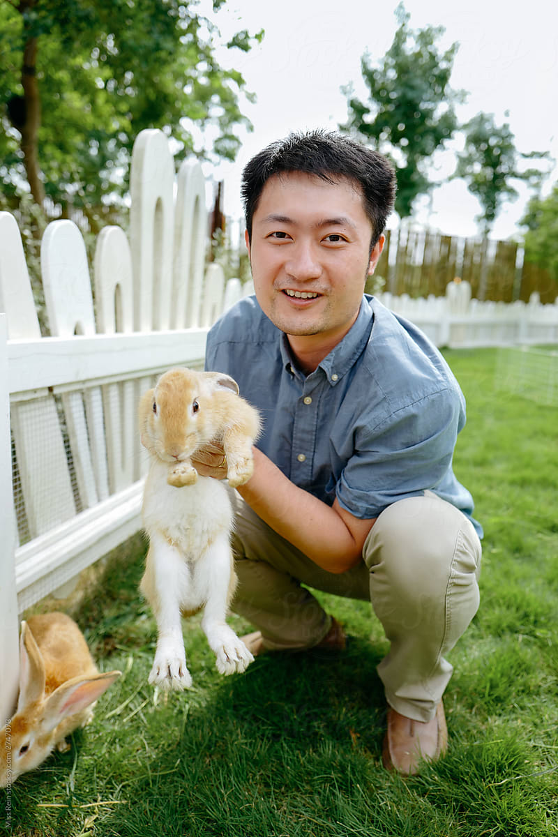 Asian young man holding a cute expression rabbit in the garden