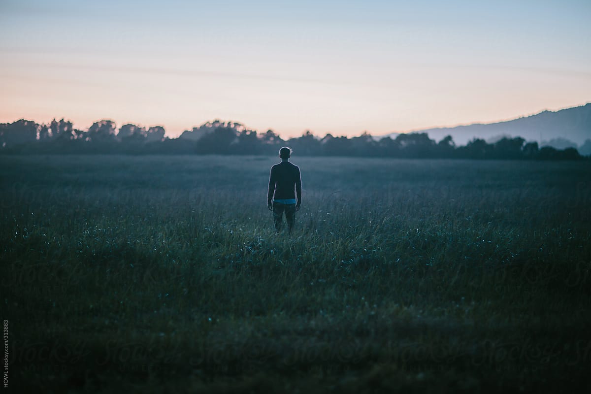 Young man stands alone in a field of solitude.