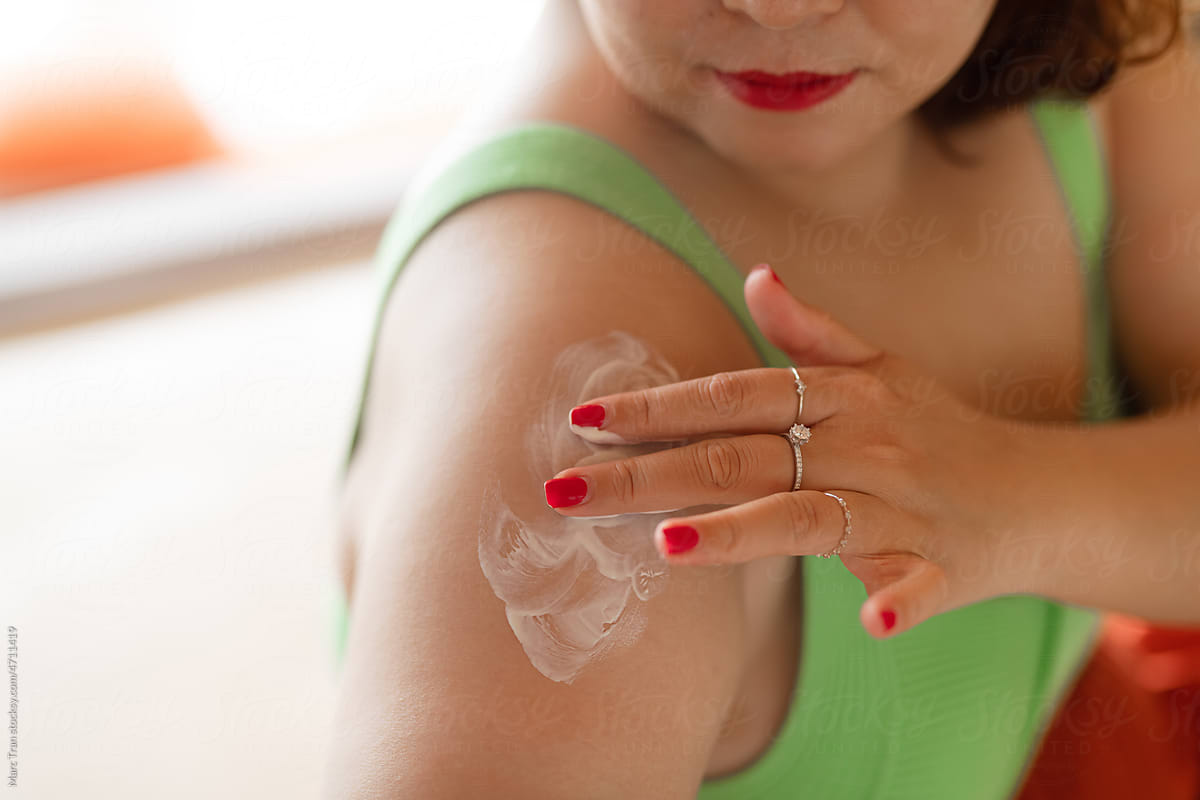 Woman applying sunscreen creme on the shoulder