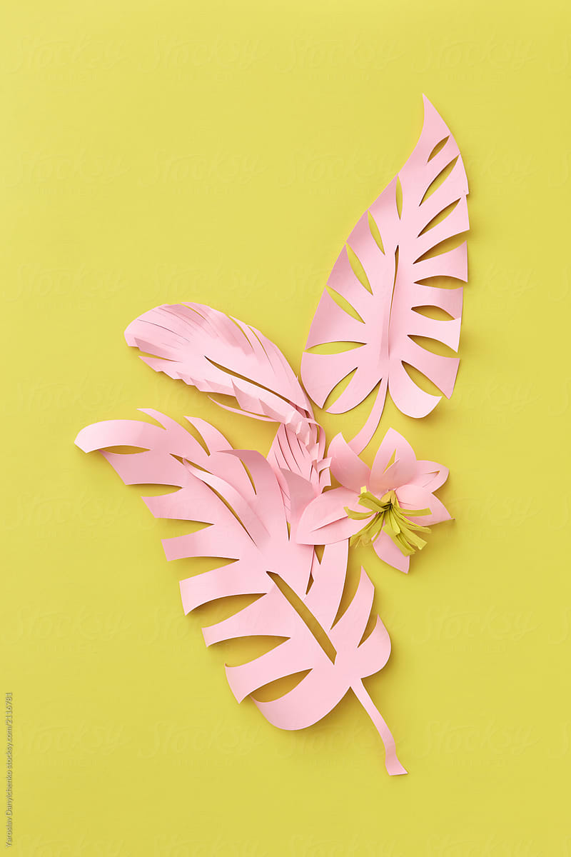 Handmade flowers and leaf, cut from colored paper on a yellow ba