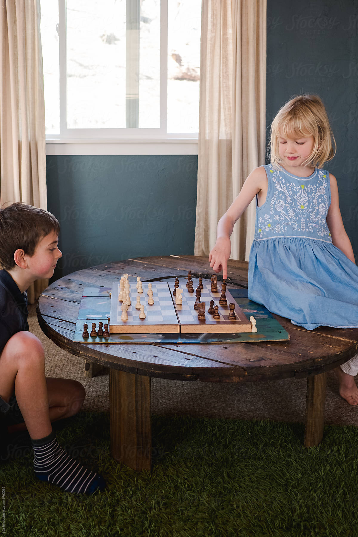 kids playing a game of chess, little girl pointing to a piece of the game.