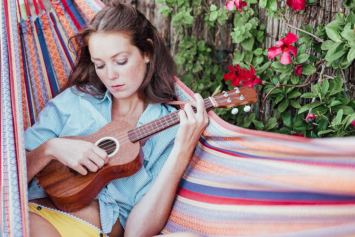 Young woman playing ukulele in a hammock