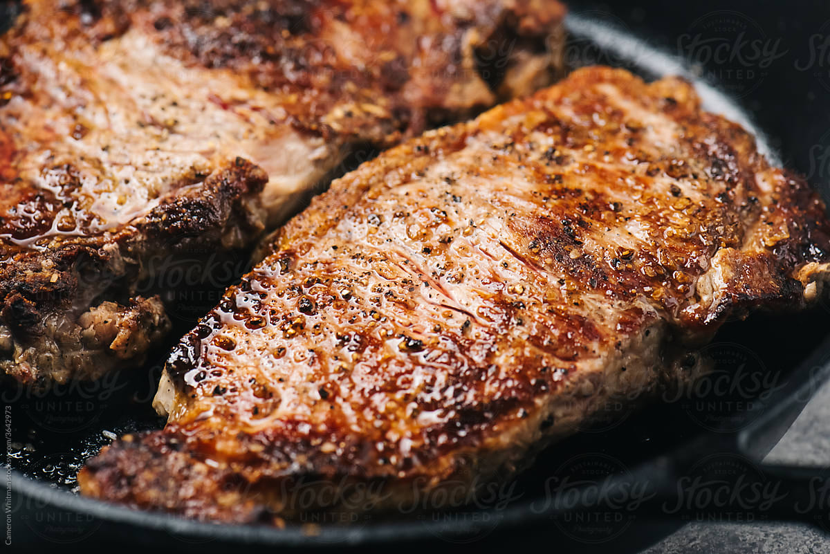 Closeup of NY Strip Steak cooking in an iron skillet