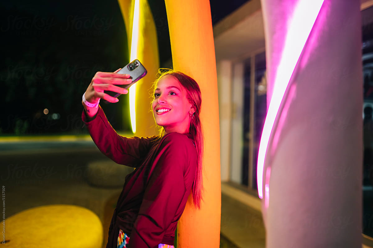 Cuban female taking selfie near illuminated columns