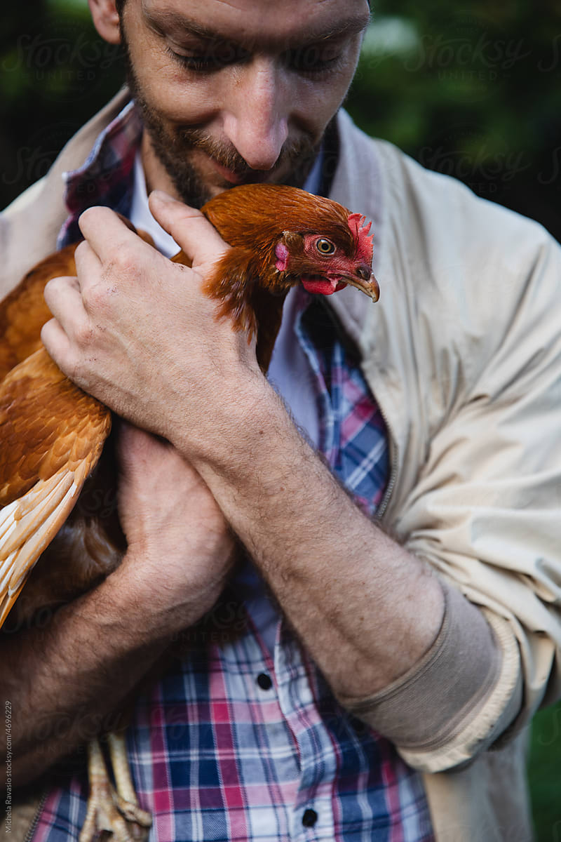 Man clutching hen to chest
