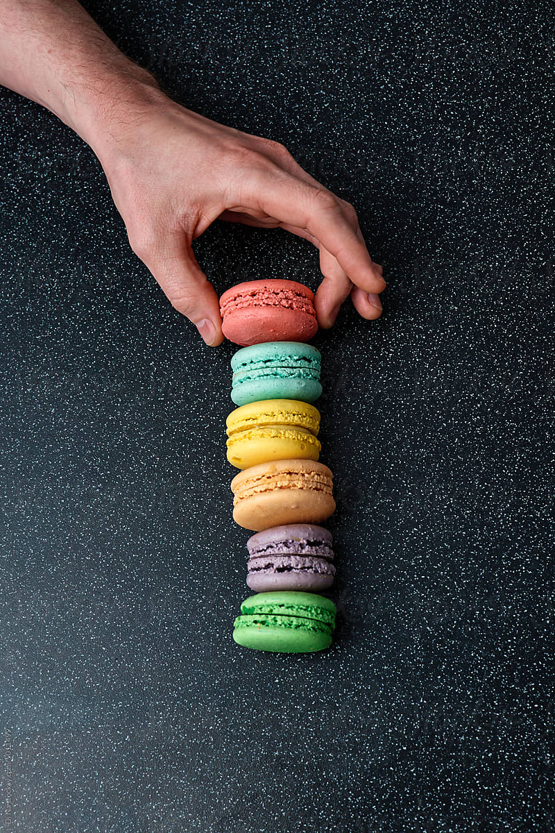 Anonymous hand stacks macaroons on the table