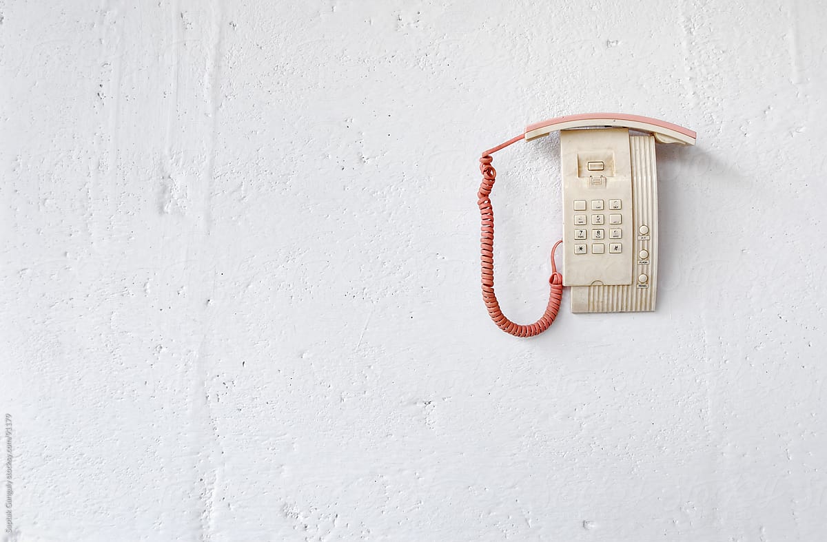 Dead telephone hanging on white wall