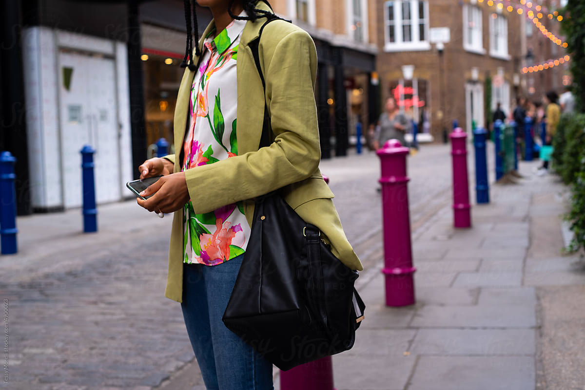 Black woman holding phone in her hands and a weekender bag
