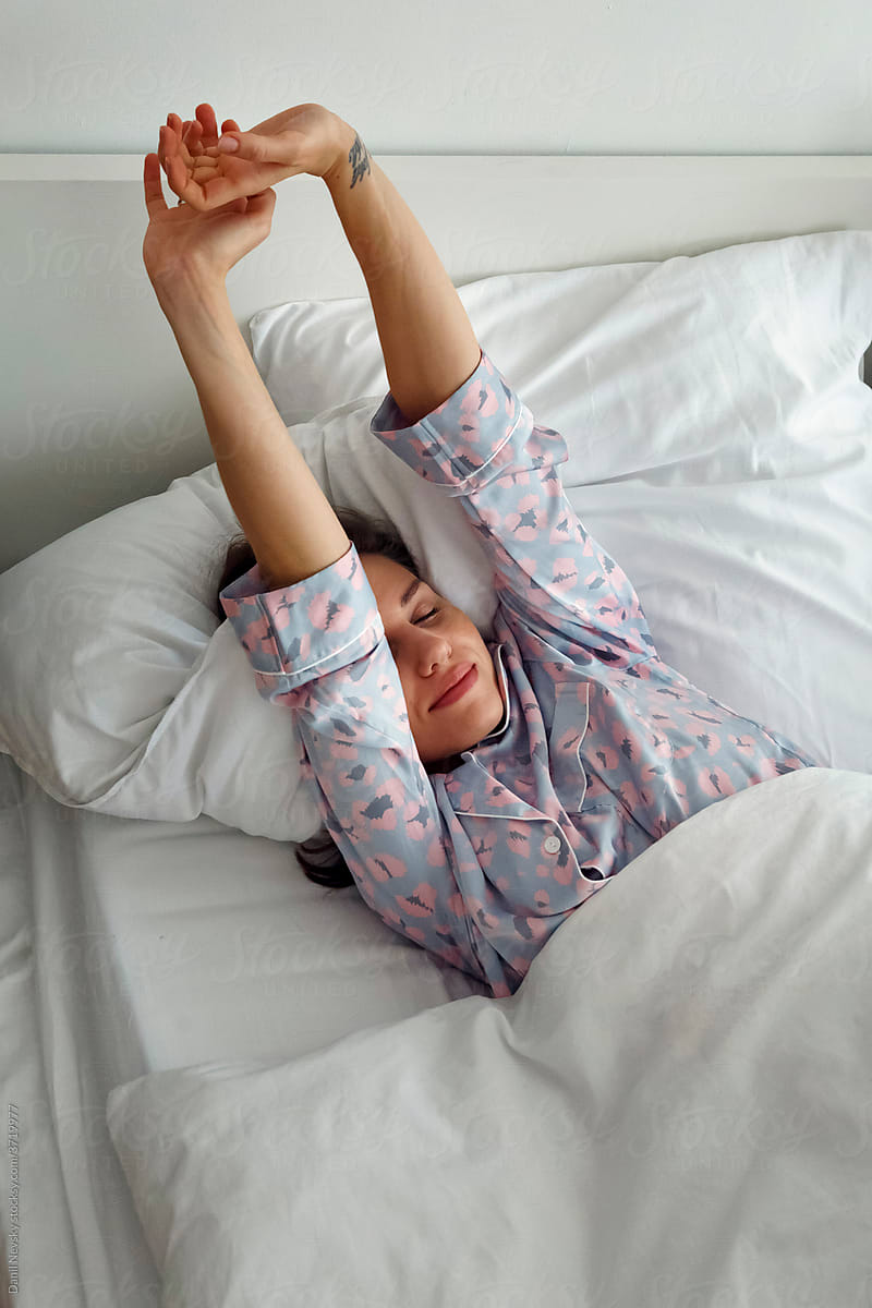Young woman stretching arms in bed