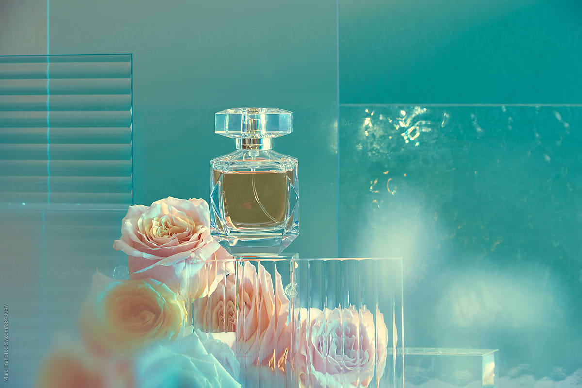 Perfume bottle on glass podium. Floral arrangement