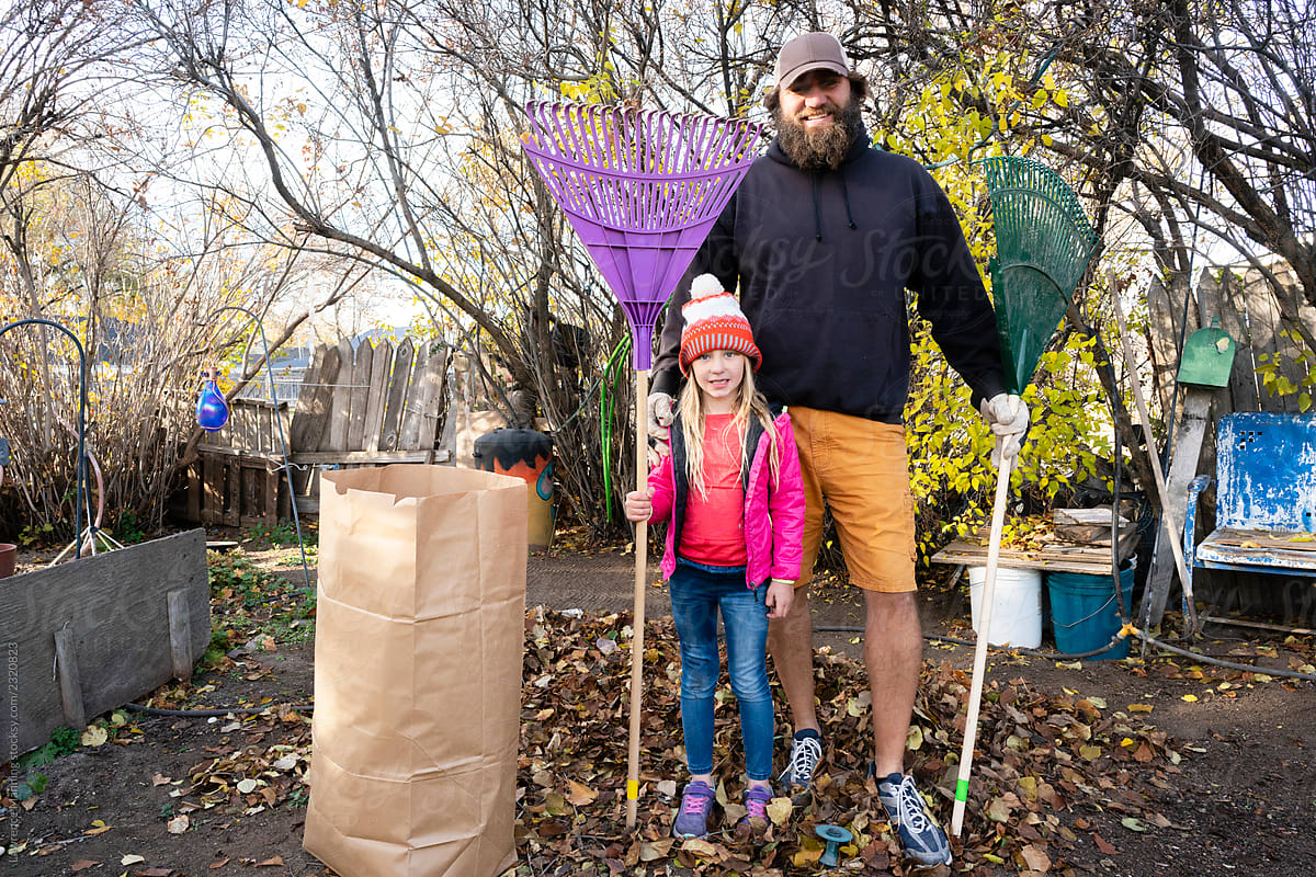 Father and Daughter volunteers raking autumn leaves