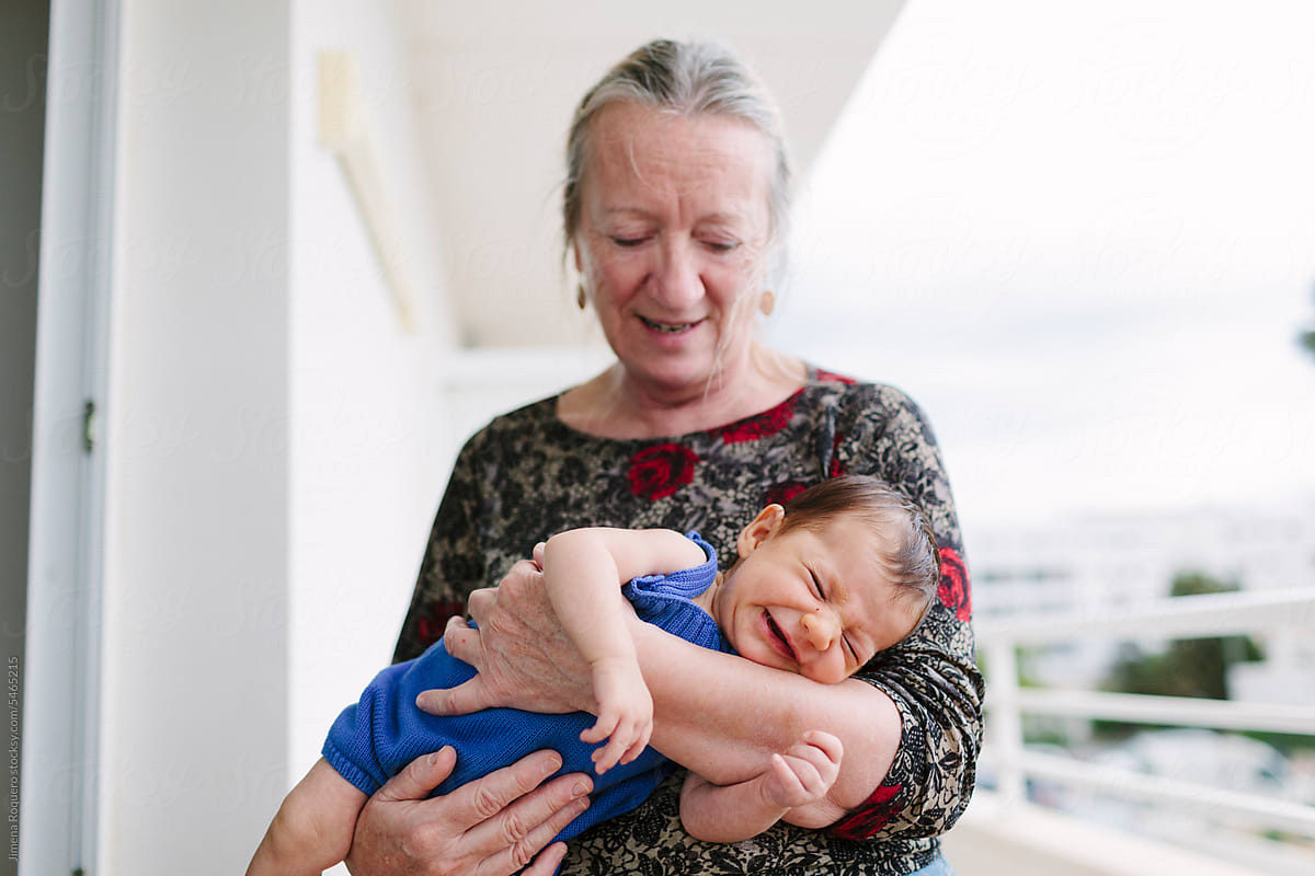 Grandma holding crying newborn in apartment terrace